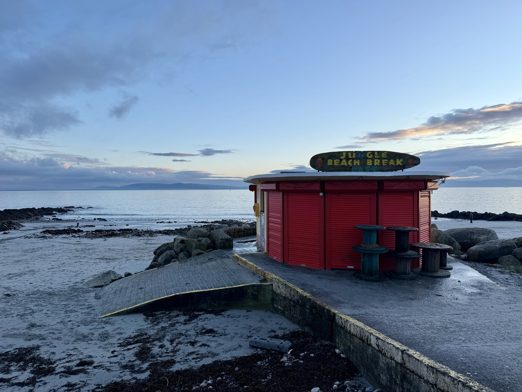 The Jungle Beach Break kiosk closed for the evening on the Salthill promenade, Galway Bay stretching out behind it at dusk