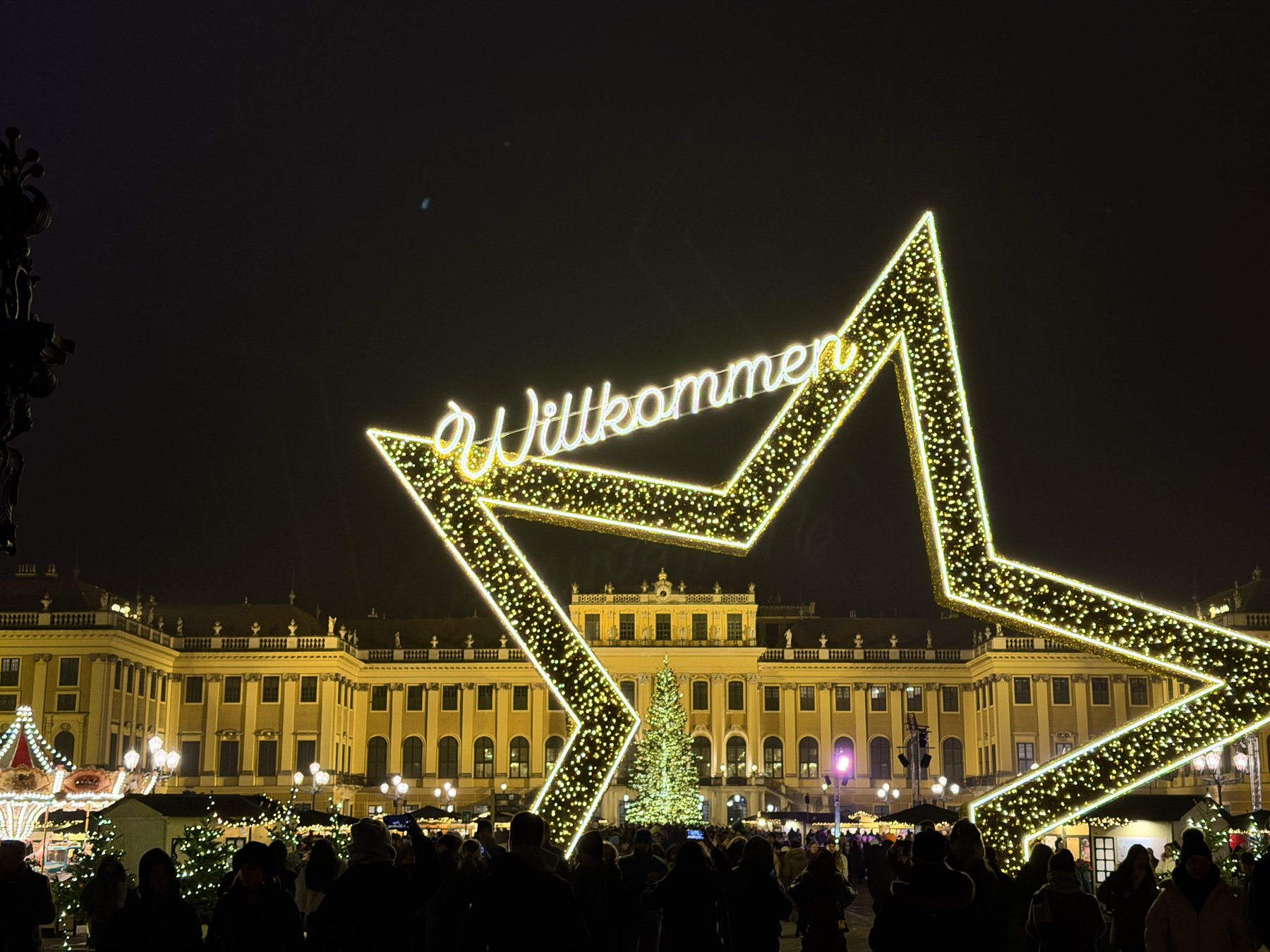 "Willkommen" illuminated star sign at Schönbrunn Palace Christmas market at night, Vienna