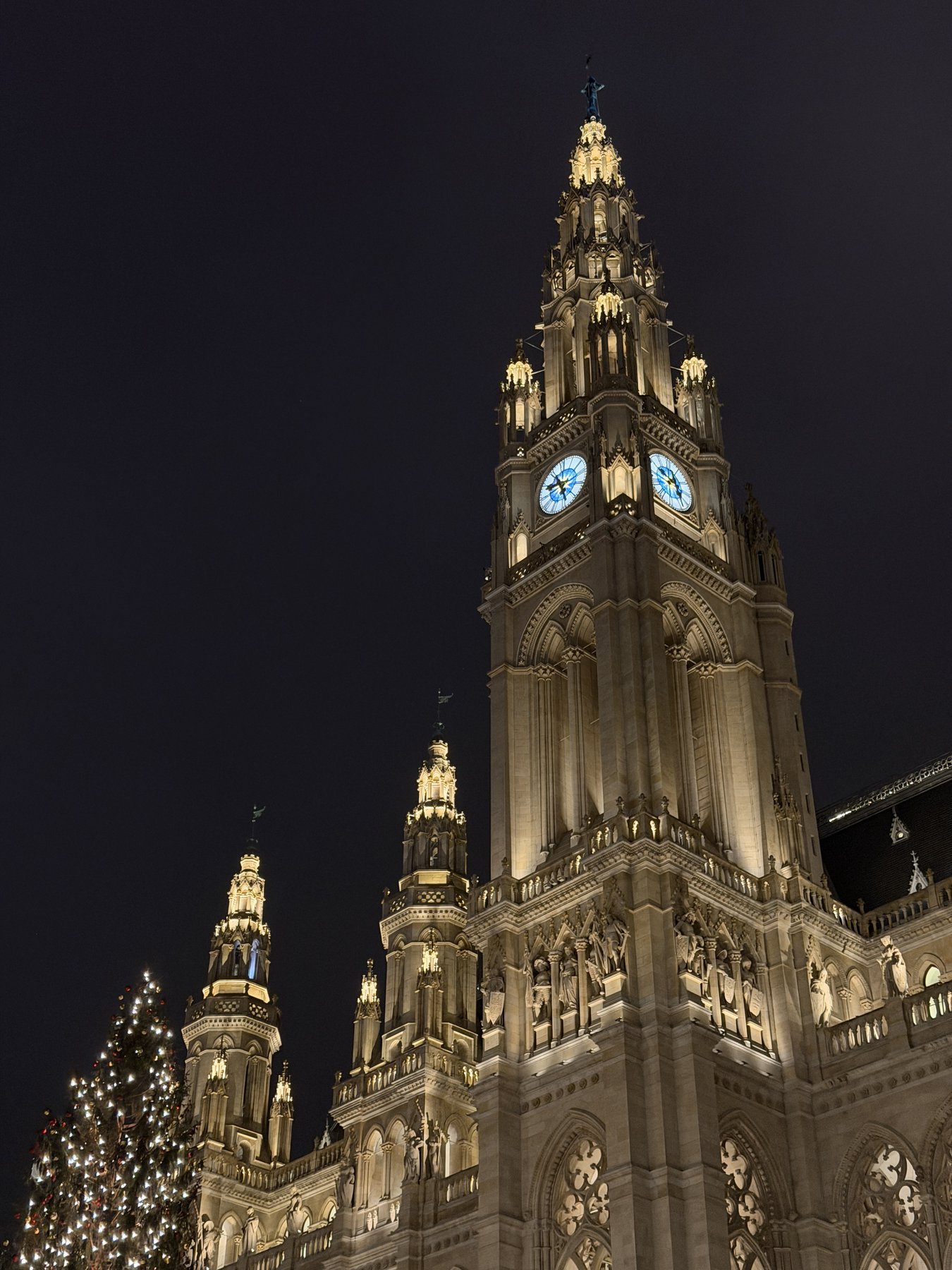 Vienna City Hall (Rathaus) illuminated at night, Gothic spires soaring against a dark sky with a Christmas tree at its base